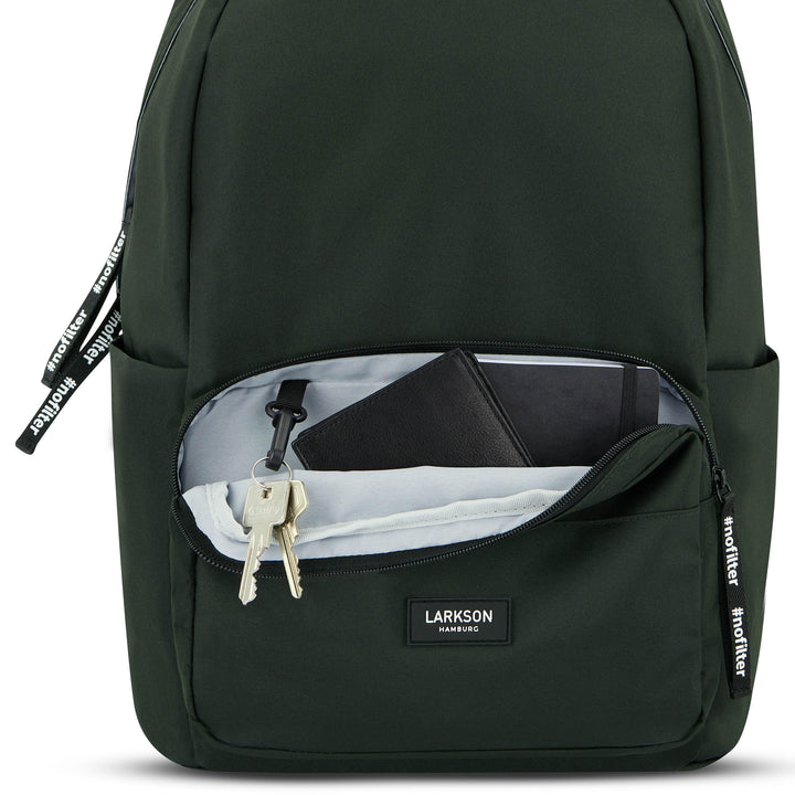 Dunkelgrüner LARKSON Rucksack No 3 mit geöffnetem Frontfach, Schlüsselanhänger, schwarzem Notizbuch und hellem Stoff
