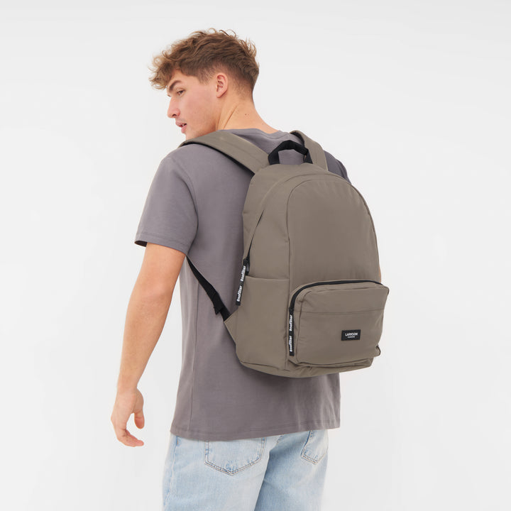 Junger Mann mit grauem T-Shirt und hellblauen Jeans trägt einen LARKSON Rucksack No 3 in Gravel-Farbe auf dem Rücken