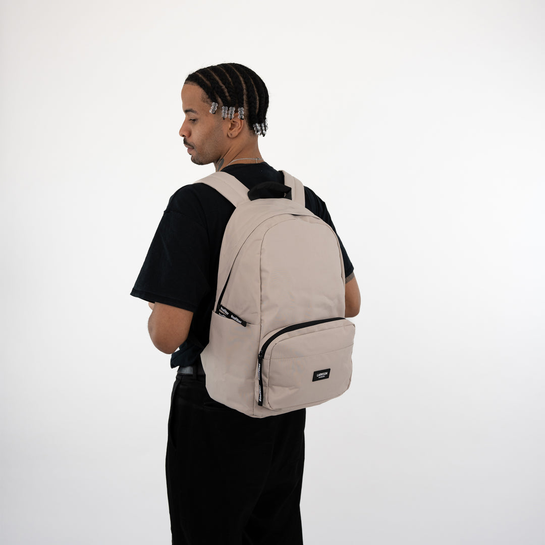 Mann mit beige LARKSON Rucksack No 3, seitlich, schwarzes T-Shirt, weißer Hintergrund
