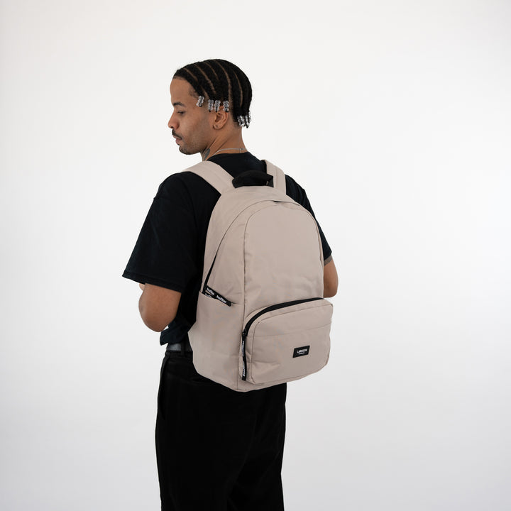 Mann mit beige LARKSON Rucksack No 3, seitlich, schwarzes T-Shirt, weißer Hintergrund