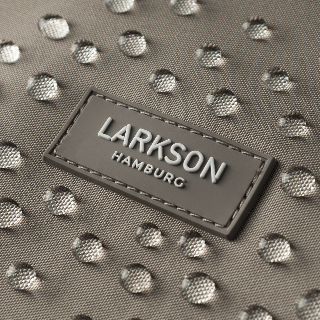 Nahaufnahme eines grauen LARKSON-Labels auf wasserabweisendem Stoff mit Wassertropfen