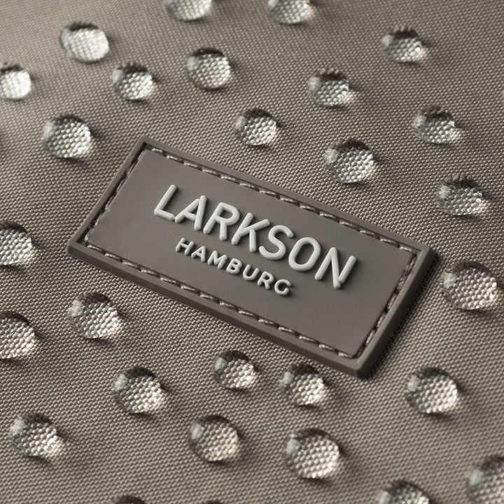 Nahaufnahme eines grauen LARKSON-Labels auf wasserabweisendem Stoff mit Wassertropfen