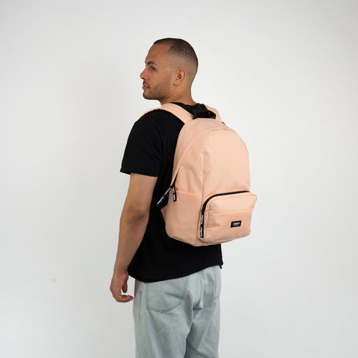 Mann mit hellem Pfirsichfarbener LARKSON Rucksack No 3, schwarzes T-Shirt, hellblaue Jeans