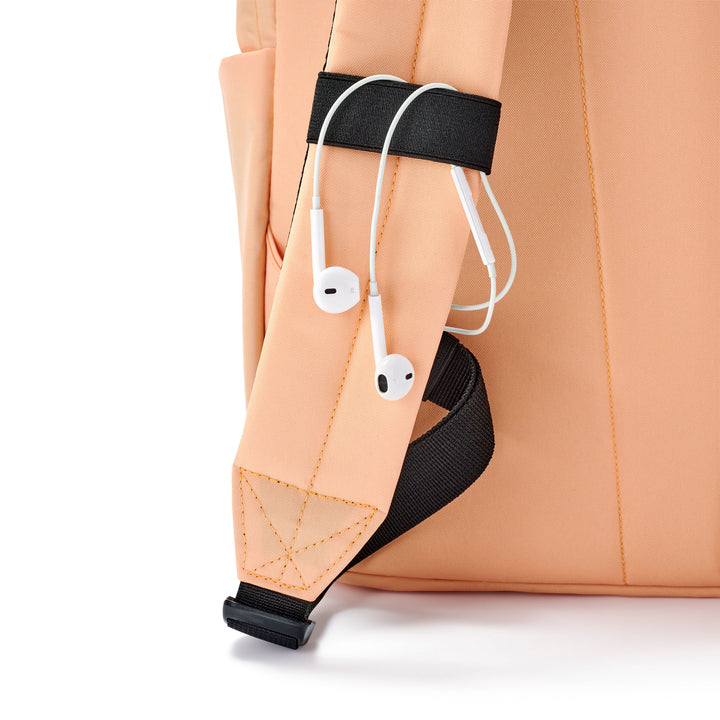 Detail des hellpfirsichfarbenen LARKSON Rucksack No 3 mit Kopfhörern befestigt am Schultergurt