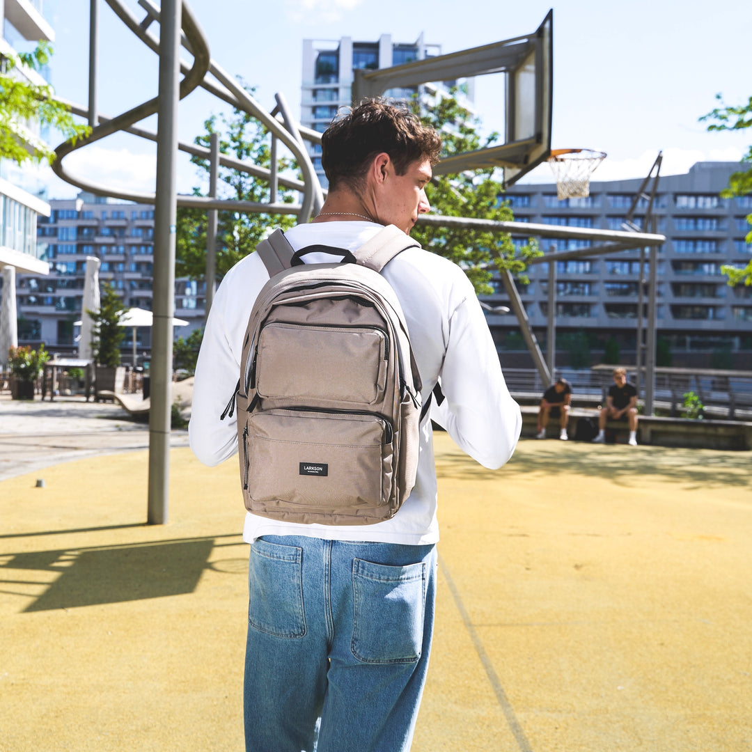 Jugendlicher mit beigem LARKSON Rucksack 'Rucksack No 3 Advanced' auf einem Basketballplatz