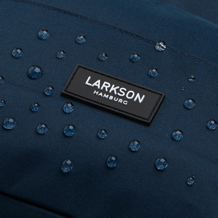 Nahaufnahme des blauen Larkson Rucksacks No 3 mit wasserabweisender Oberfläche und Logo auf der Vorderseite