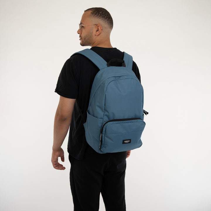Mann mit schwarzem T-Shirt trägt modernen blauen Schulrucksack Rucksack No 3 von LARKSON