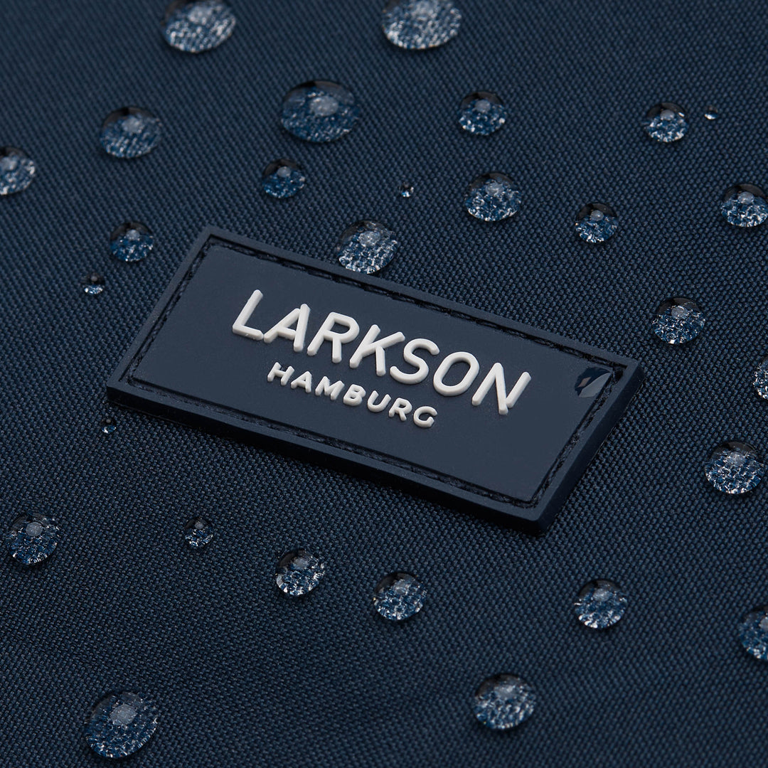 Logo 'LARKSON Hamburg' auf dunkelblauem, wasserabweisendem Rucksackmaterial mit Wasserperlen