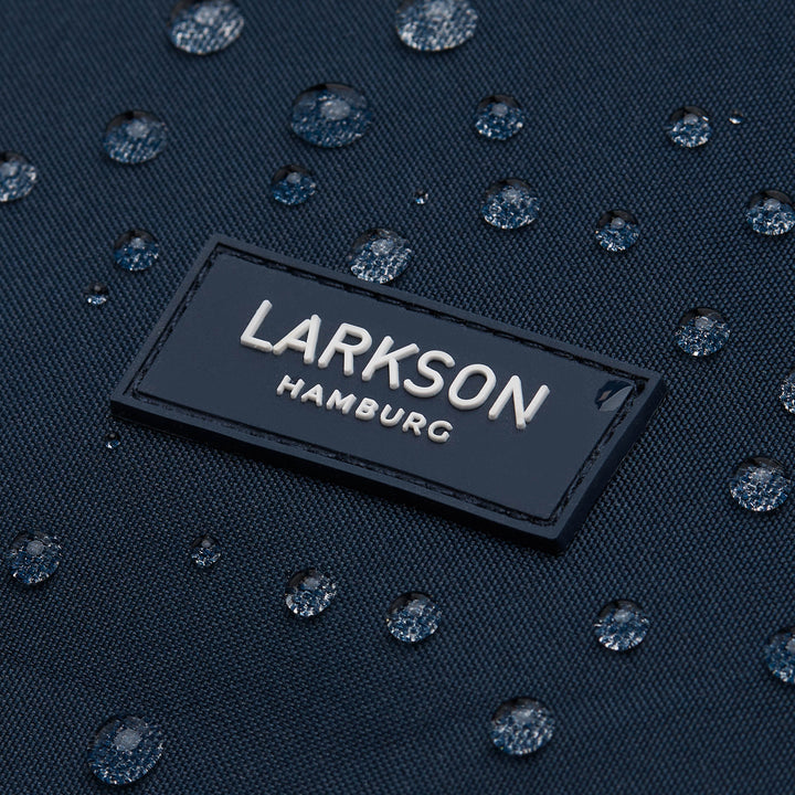 Logo 'LARKSON Hamburg' auf dunkelblauem, wasserabweisendem Rucksackmaterial mit Wasserperlen