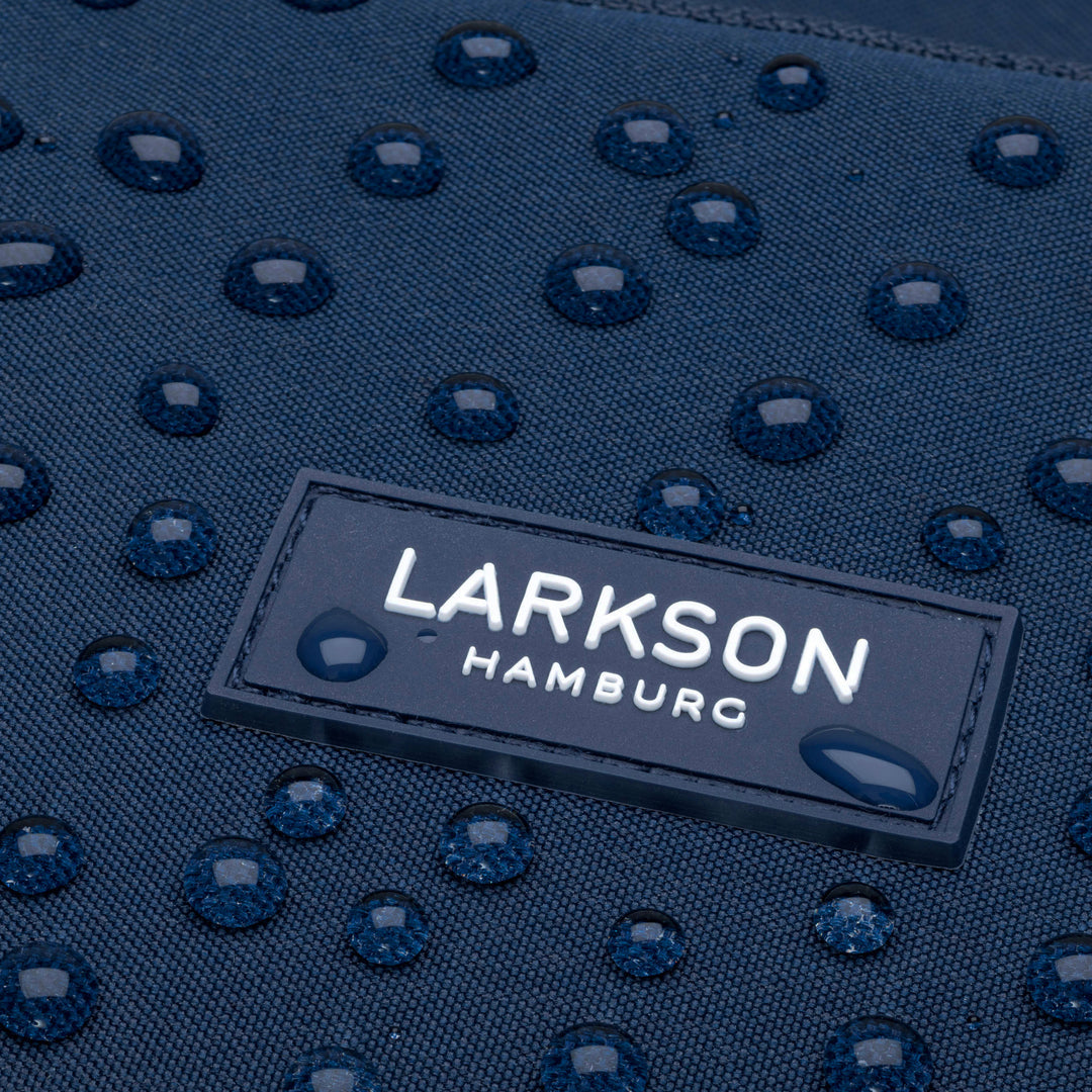Nahaufnahme des wasserabweisenden dunkelblauen Materials mit Wassertropfen und LARKSON HAMBURG Logo am Rucksack No 6