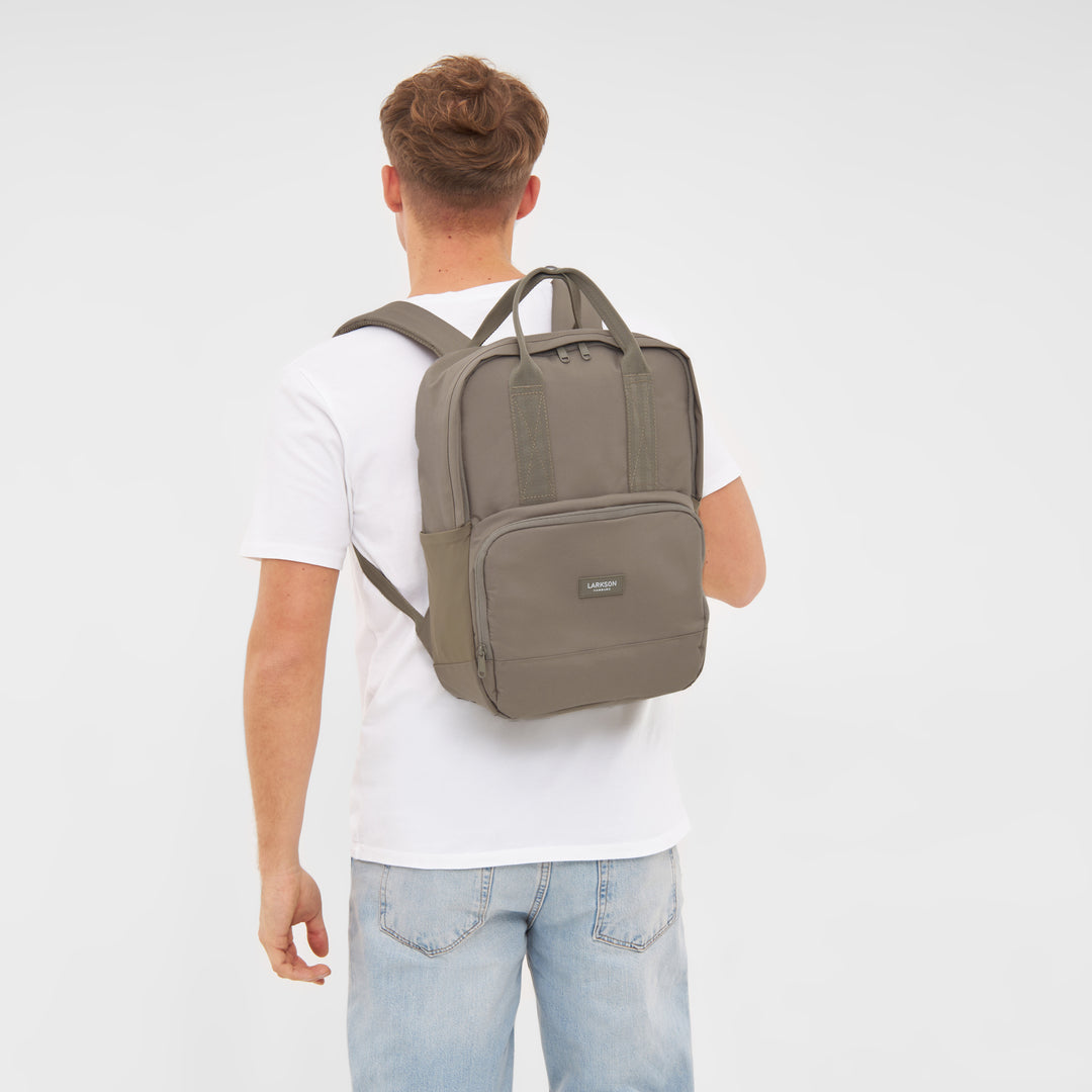 Mann trägt LARKSON Rucksack No 6 in Gravelgrau mit Fronttasche und Griffen