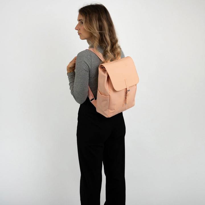 Frau mit grauem Langarmshirt und schwarzer Hose trägt hellrosa Rucksack Ida mit Umschlagklappe