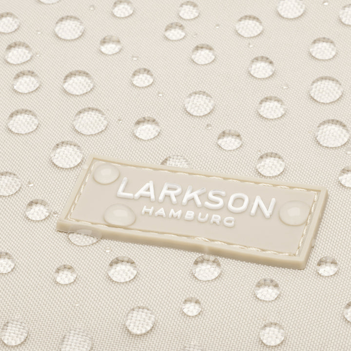 Detailaufnahme des wasserabweisenden beigen Stoffes mit Larkson Hamburg Logo und Wassertropfen
