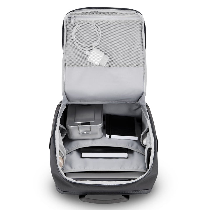 Geöffneter grauer Rucksack Niklas mit Innenfächern, Ladekabel, Metallbox und Notizbüchern