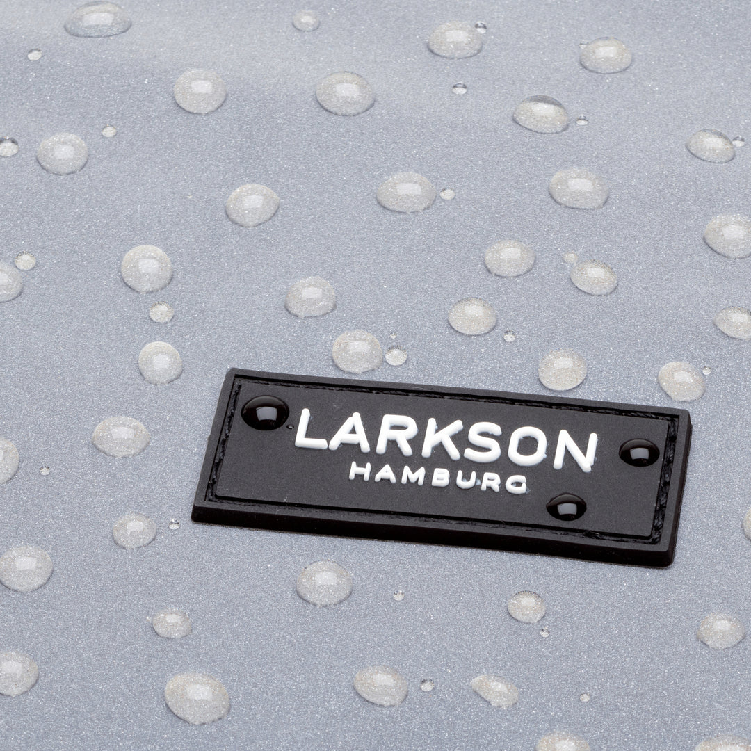 Nahaufnahme des schwarzen Logos mit weißer Aufschrift 'LARKSON HAMBURG' auf reflektierendem, wasserabweisendem Material mit Wassertropfen