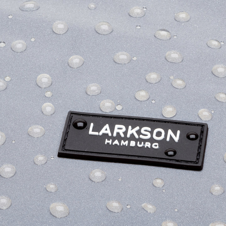 Nahaufnahme des schwarzen Logos mit weißer Aufschrift 'LARKSON HAMBURG' auf reflektierendem, wasserabweisendem Material mit Wassertropfen