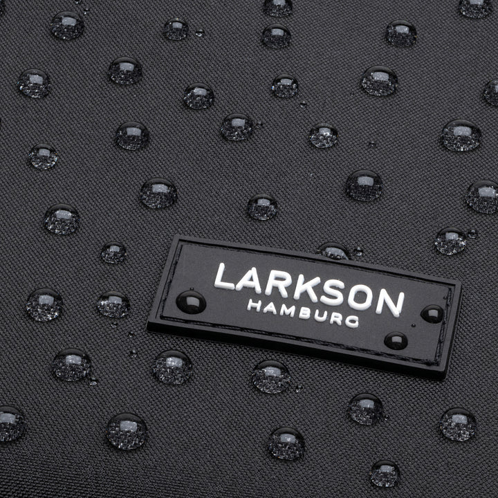 Schwarzes wasserabweisendes Material mit Wassertropfen und LARKSON Hamburg Logo auf dem Rolltop Rucksack No 2