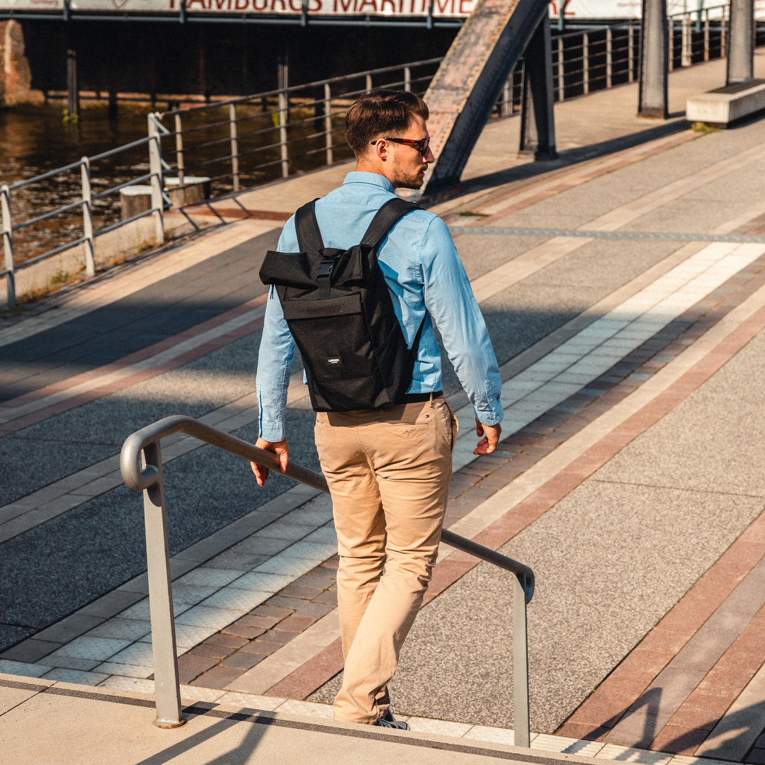 Mann trägt LARKSON Rolltop Rucksack Nr. 4 in Schwarz am Hamburger Hafen