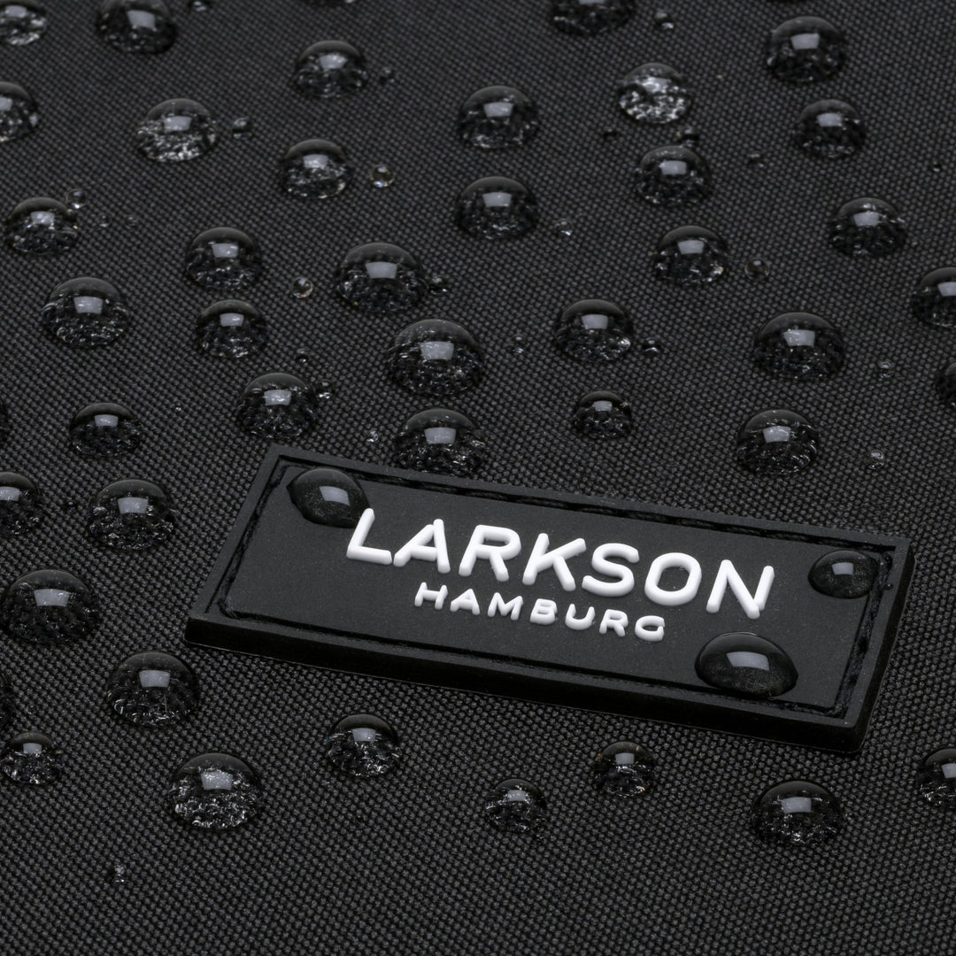 Nahaufnahme des LARKSON Hamburg Logos auf schwarzem wasserabweisendem Rucksack Niklas mit Tropfen