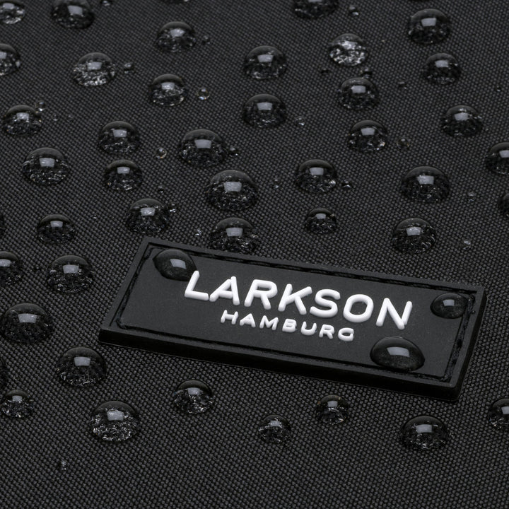 Nahaufnahme des LARKSON Hamburg Logos auf schwarzem wasserabweisendem Rucksack Niklas mit Tropfen