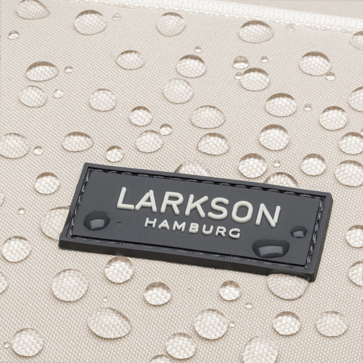 Wasserabweisendes Material mit schwarzem LARKSON Hamburg Markenetikett und Wassertropfen