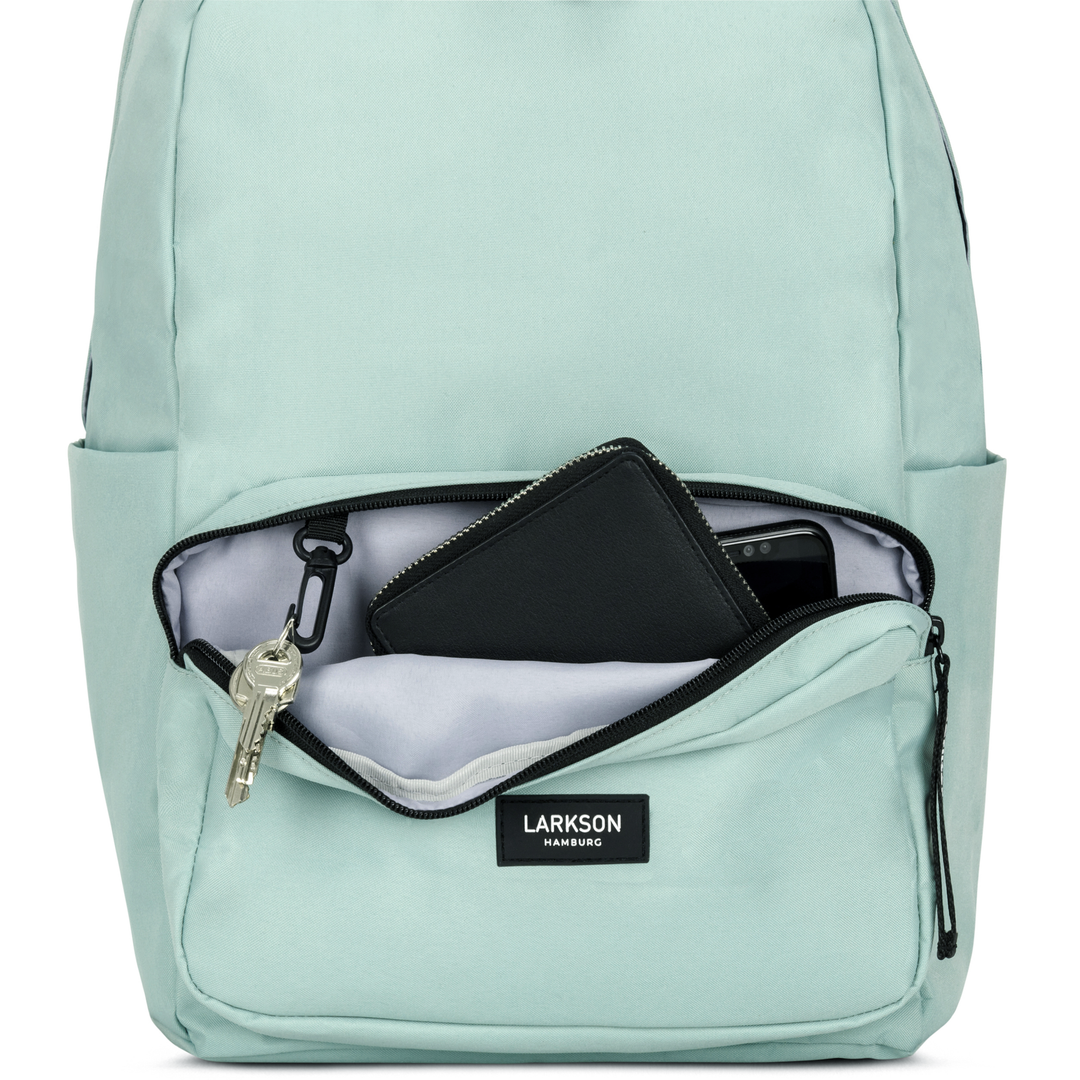 Mintfarbener LARKSON Rucksack No 3 mit geöffnetem Frontfach, darin Schlüssel, schwarzes Portemonnaie und Handy