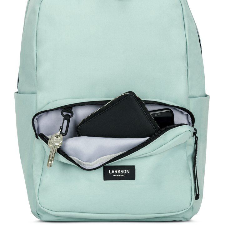 Mintfarbener LARKSON Rucksack No 3 mit geöffnetem Frontfach, darin Schlüssel, schwarzes Portemonnaie und Handy