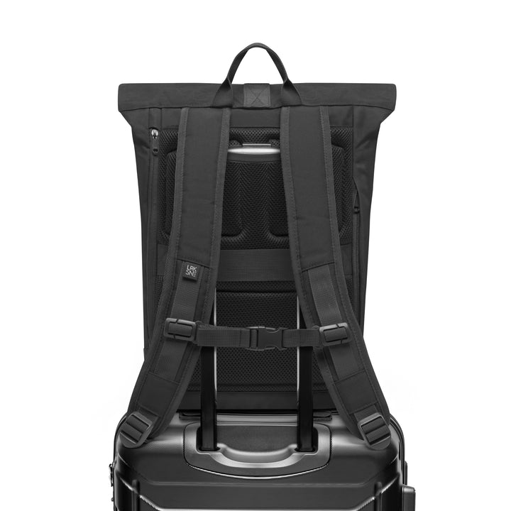 Rückansicht des schwarzen Rolltop Rucksacks Janne Small mit gepolsterten Schulterriemen und Trolley-Aufsteckvorrichtung