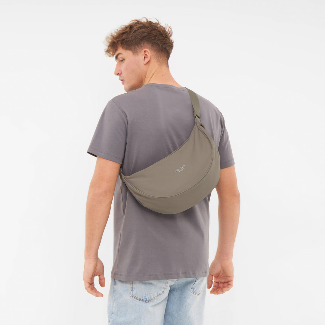 Mann von hinten mit grauem T-Shirt und halbmondförmiger, olivgrüner Half Moon Bag Solveig Medium von LARKSON