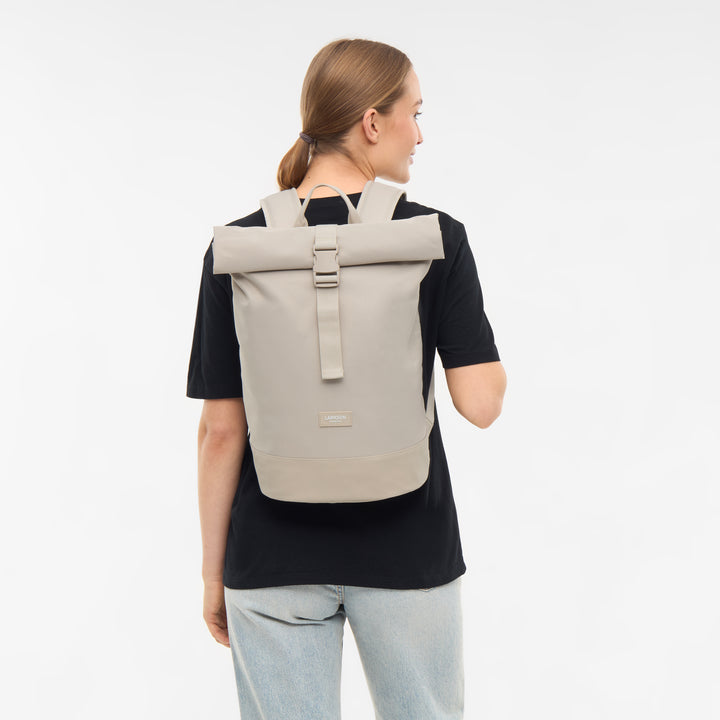Beige Rolltop-Rucksack Janne Small von LARKSON getragen von Frau mit schwarzem T-Shirt und blauer Jeans
