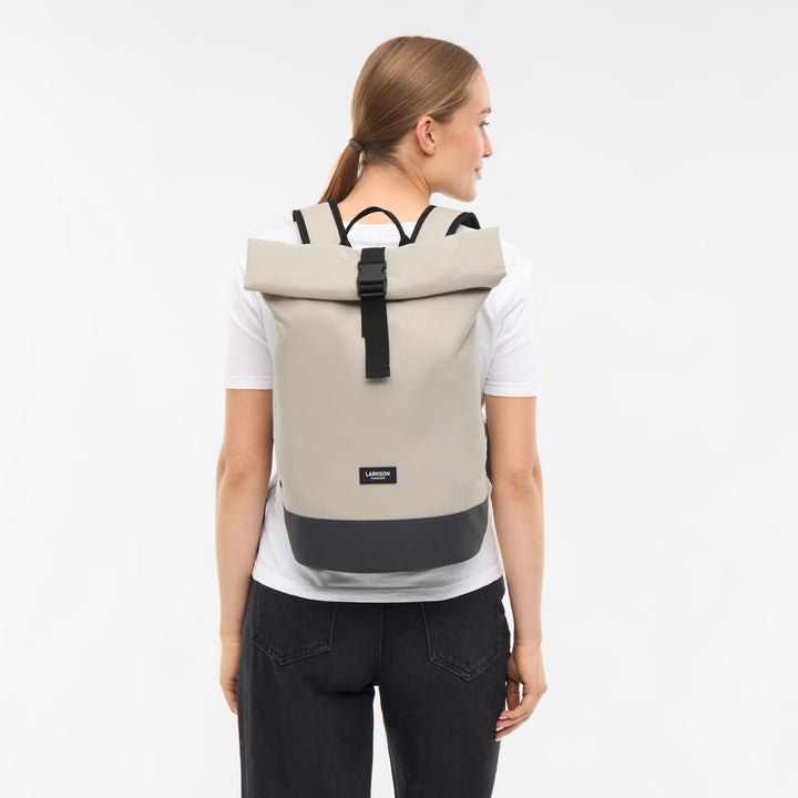 Dame mit hellem Rolltop Rucksack Janne Small von LARKSON, schwarzem Boden, weißen T-Shirt und dunkler Jeans