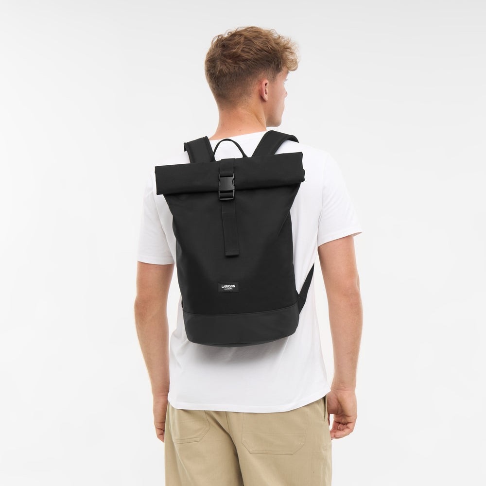 Junger Mann trägt schwarzen LARKSON Rolltop Rucksack Janne Small mit Schnallenverschluss