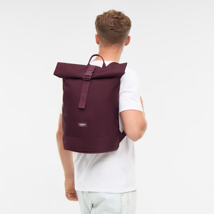 Mann trägt LARKSON Rolltop Rucksack Janne Small in dunkelrot, von hinten sichtbar