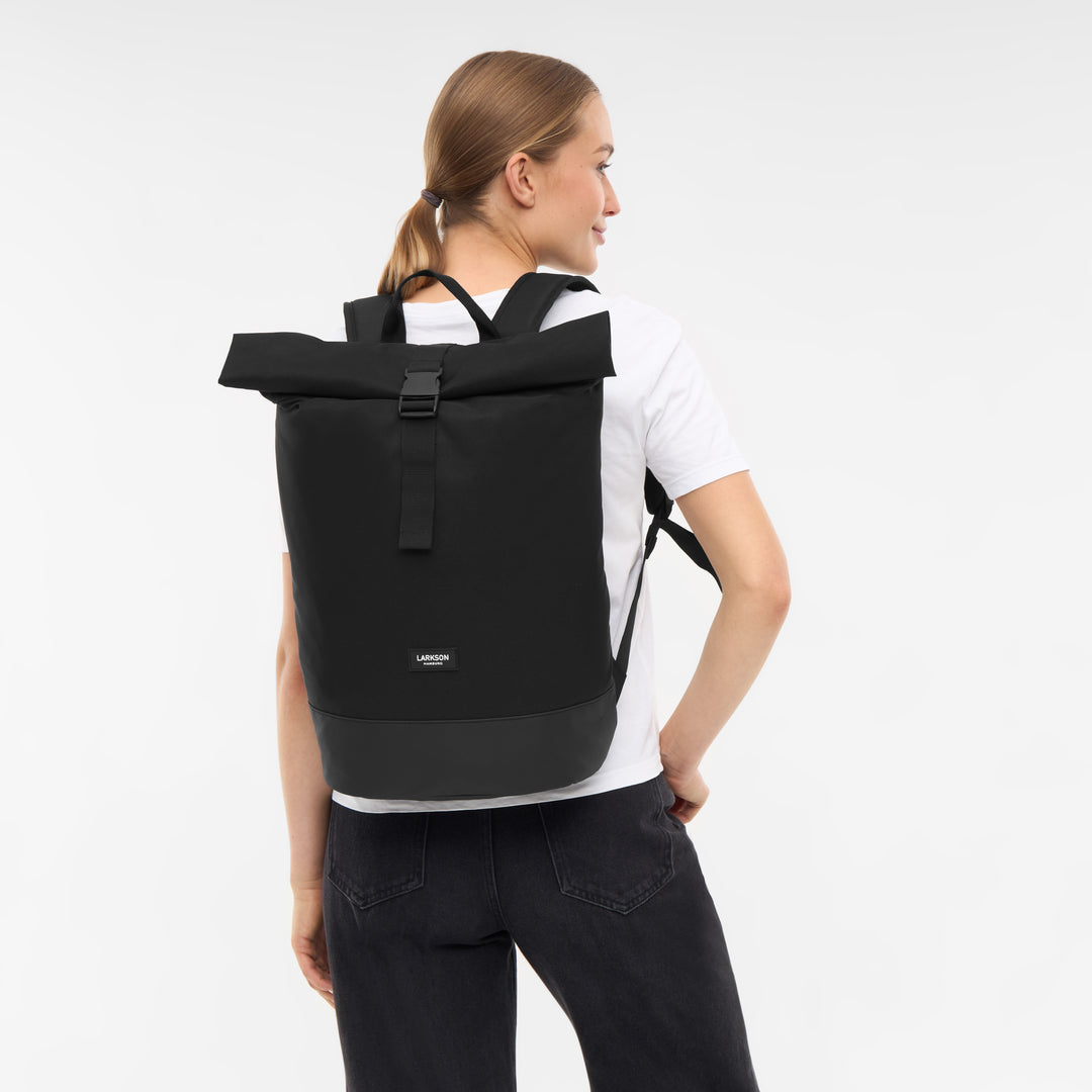 Frau mit schwarzem Rolltop Rucksack Janne von Larkson, weiße T-Shirt, schwarze Jeans