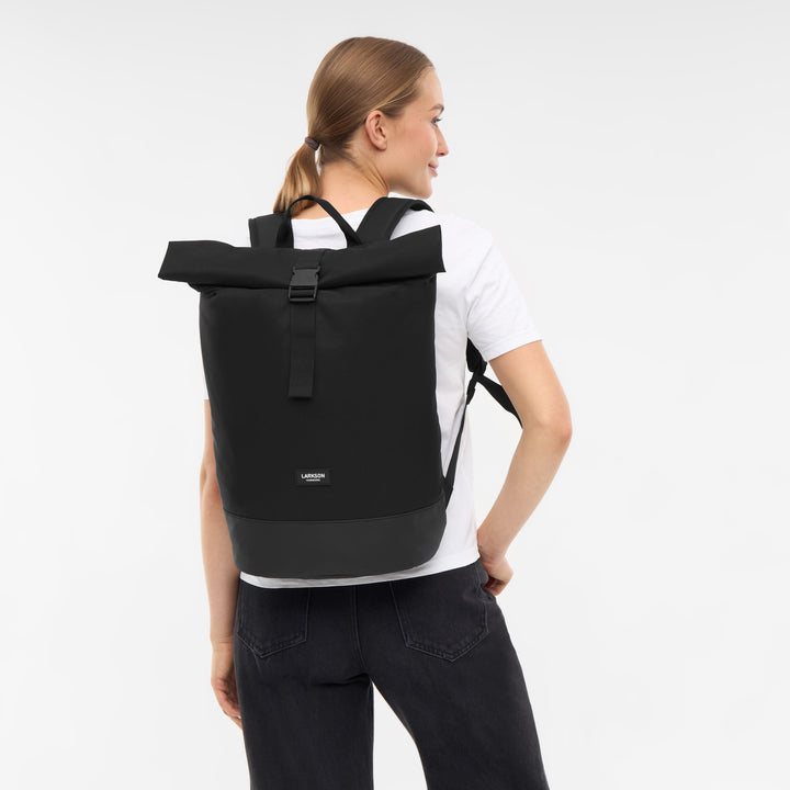Frau mit schwarzem Rolltop Rucksack Janne von Larkson, weiße T-Shirt, schwarze Jeans