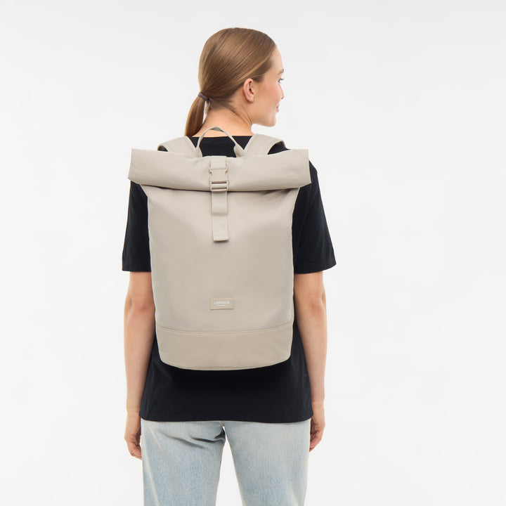 Frau mit hellbeigem LARKSON Rolltop Rucksack Janne, schwarzes T-Shirt, helle Jeans