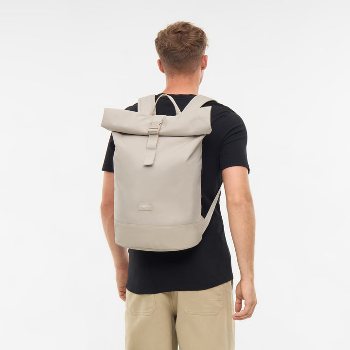 Mann von hinten mit beigem LARKSON Rolltop Rucksack Janne aus Stoff