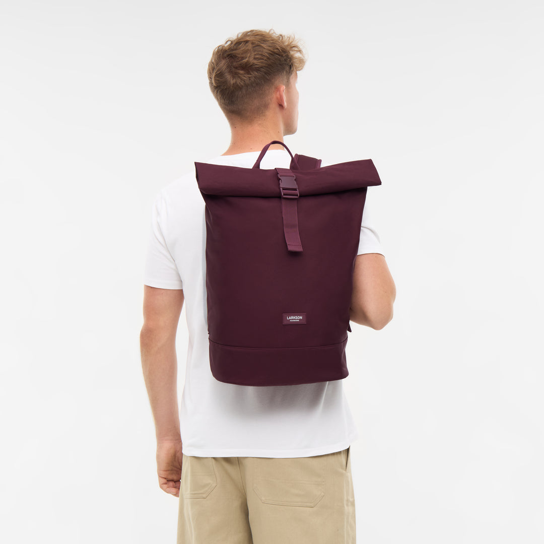 Mann trägt burgunderroten Rolltop Rucksack Janne von LARKSON, Blick von hinten