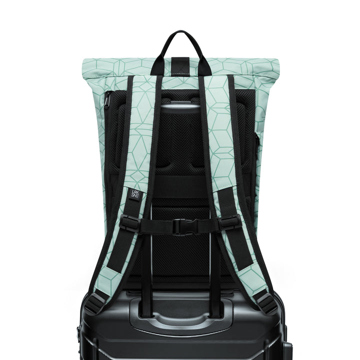 Rolltop Rucksack Janne Small in Mint mit geometrischem Muster von hinten, darauf befestigt an schwarzem Rollkoffer