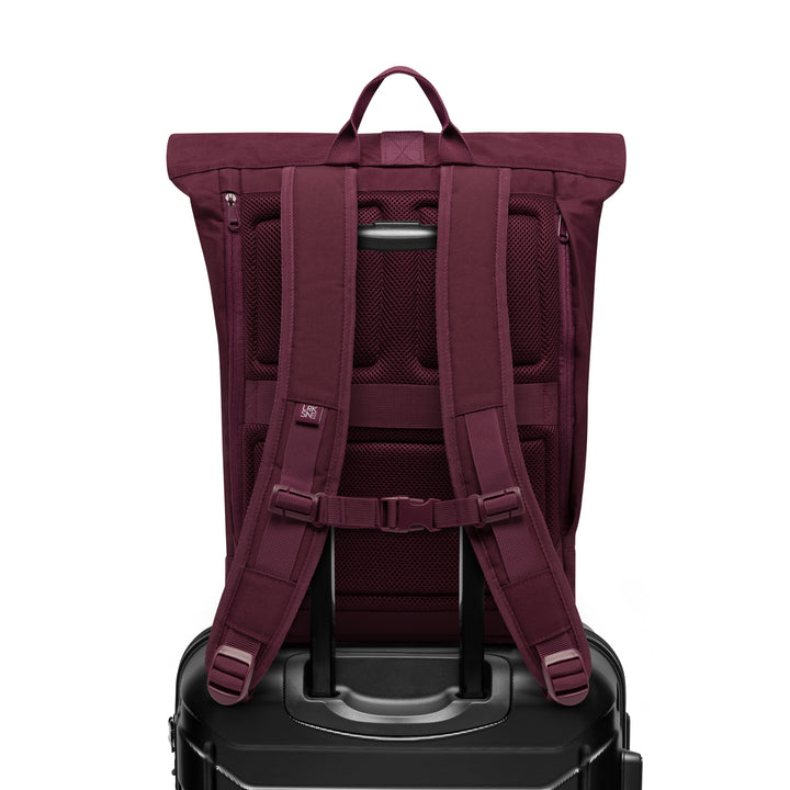 Rolltop Rucksack Janne von LARKSON in Burgund, auf schwarzem Reisekoffer befestigt