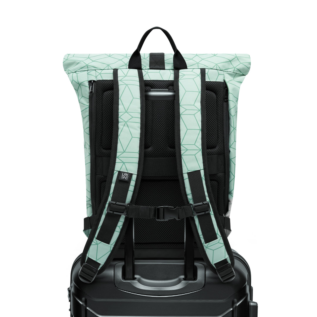 Mintgrüner Rolltop Rucksack 'Janne' mit geometrischem Muster und gepolsterten Schultergurten auf schwarzem Koffer
