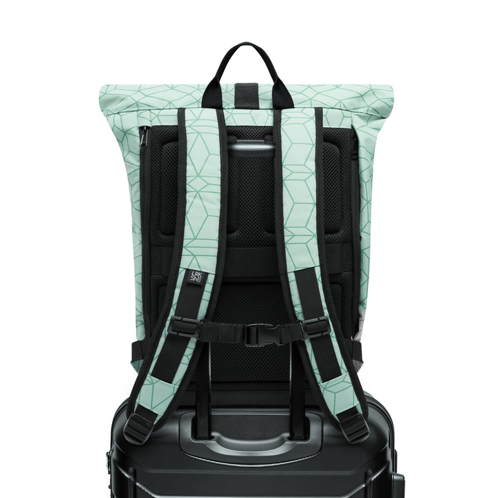 Mintgrüner Rolltop Rucksack 'Janne' mit geometrischem Muster und gepolsterten Schultergurten auf schwarzem Koffer