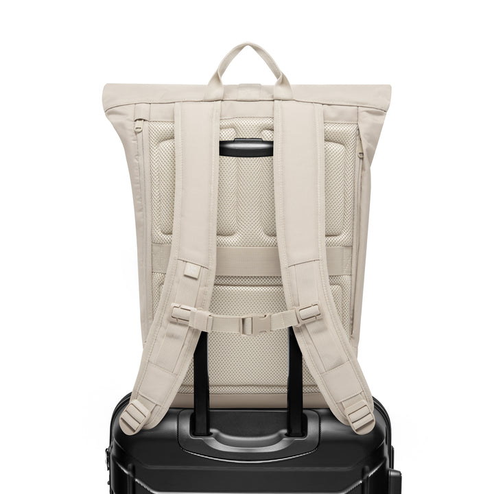 Rückansicht des sandfarbenen Rolltop Rucksack Janne auf einem schwarzen Trolleygriff