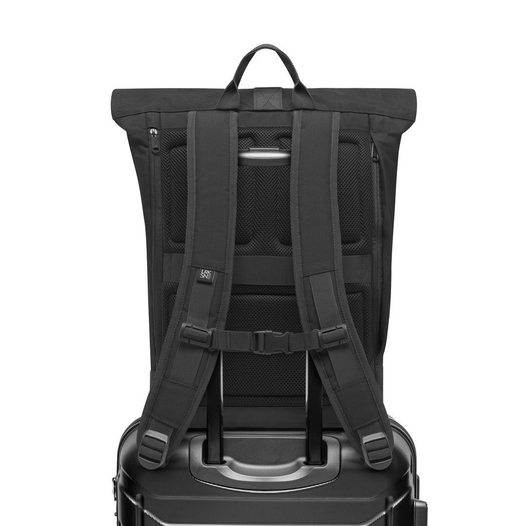 Rückansicht des schwarzen Rolltop Rucksacks Janne von LARKSON auf einem Trolleygriff