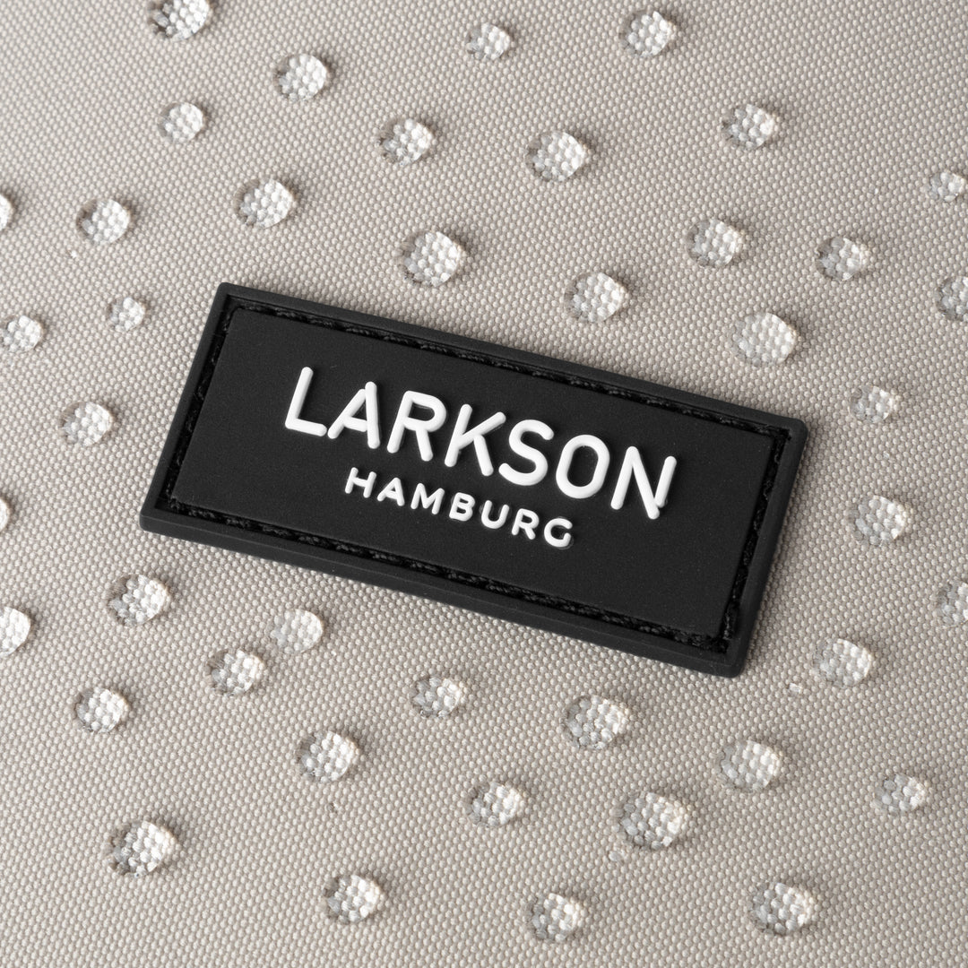Nahaufnahme des LARKSON Hamburg Logos auf sandgrauem wasserabweisendem Rolltop Rucksack Janne