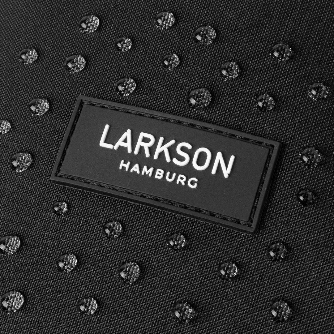 Nahaufnahme des wasserabweisenden schwarzen Stoffes mit LARKSON Hamburg Logo und Wassertropfen